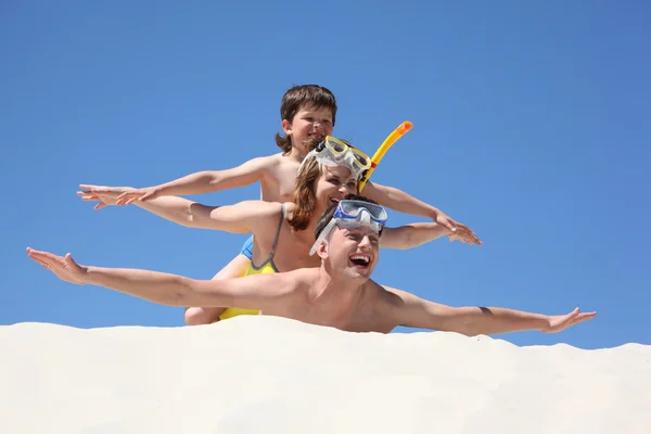 Familie met zoon liggend op het zand met snorkelen maskers — Stockfoto