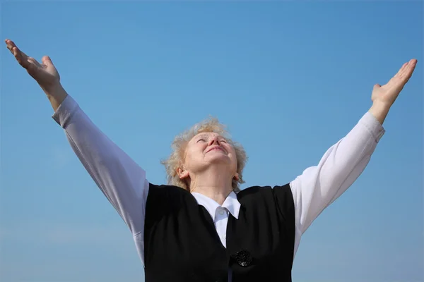Пожилая женщина с поднятыми руками смотрит в небо — стоковое фото