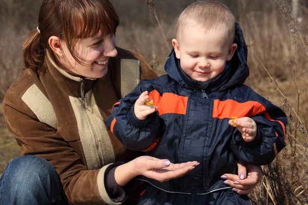 Mother with child and first flower in spring in hand — Stock Photo, Image