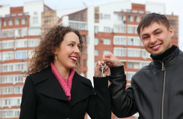 Ungt par med nyckel mot många våningar hus — Stockfoto