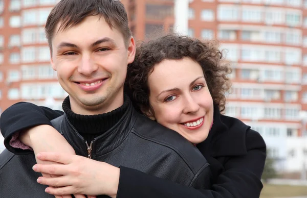Молодая пара обнимает и улыбается против строительства — стоковое фото