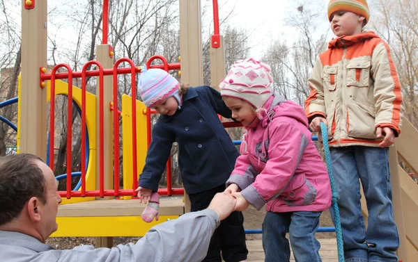 Anciano con niños en el parque infantil —  Fotos de Stock