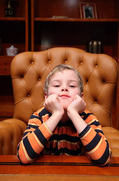 Boy est assis dans un fauteuil en cuir dans un bureau de luxe — Photo