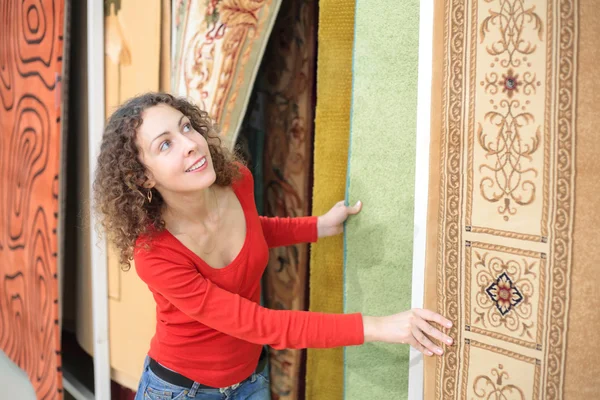 Jonge vrouw in winkel met tapijten — Stockfoto