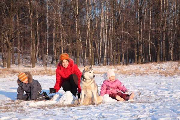Μητέρα με τα παιδιά και το σκυλί στο ξύλο το χειμώνα — Φωτογραφία Αρχείου
