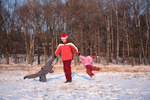 Father rotate children in wood in winter — Stock Photo, Image