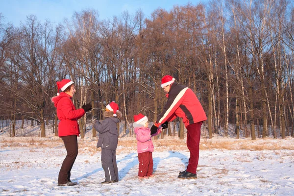 Родители и дети в красных хижинах зимой играют в лесу — стоковое фото