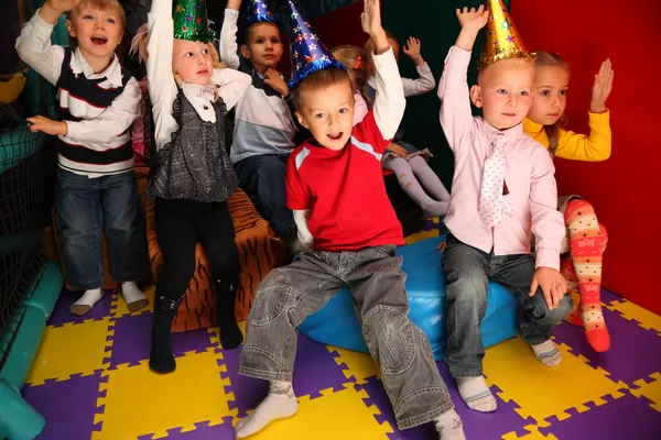 Children on holiday in kindergarten with raised hands — Stock Photo, Image