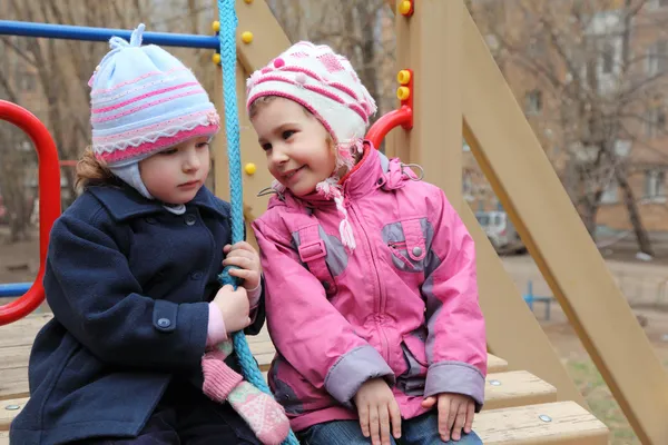 Duas meninas sentam-se no parque infantil — Fotografia de Stock