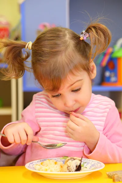 Little girl eats in kindergarten — Stock Photo, Image