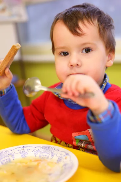 Мальчик ест в детском саду — стоковое фото