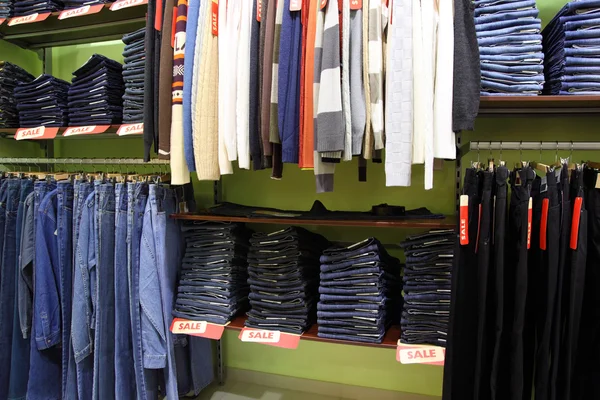 Planken en rekken met kleren in winkel — Stockfoto