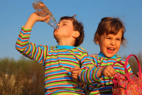 Duas crianças com t-shirts listradas, bebidas de garrafa, gir — Fotografia de Stock