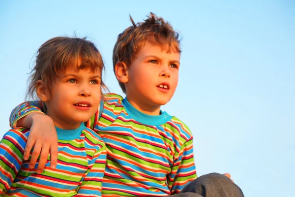 Двое детей в полосатых футболках, мальчик обнимает девушку за плечо — стоковое фото