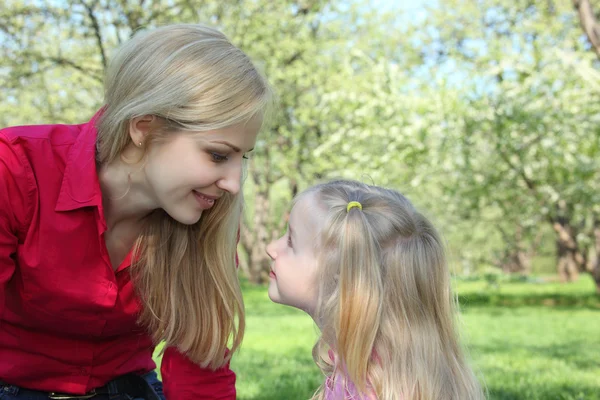 Mother and daughter look on each other in park in spring — Stock Photo, Image