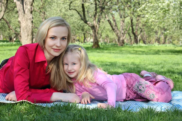 Mother with daughter lie on grass in park in spring — Stock Photo, Image