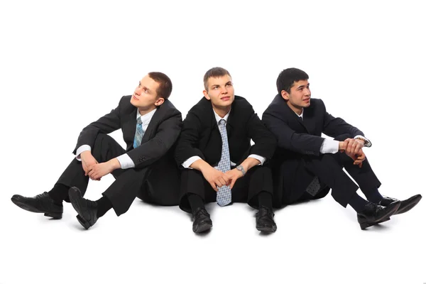 Tre giovani uomini d'affari si siedono sul pavimento e guardano in ogni direzione — Foto Stock