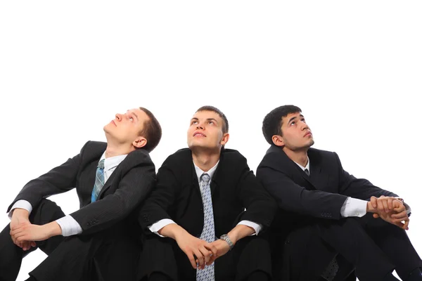 Három fiatal üzletemberek padló ülni, és nézni felfelé — Stock Fotó