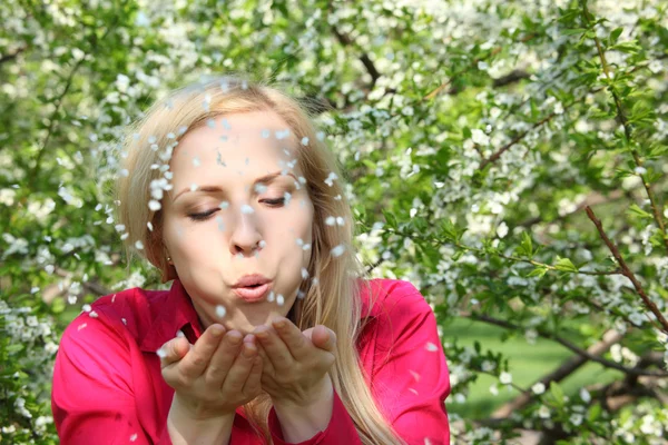 Jonge vrouw schoonheid blazen af bloemblaadjes — Stockfoto