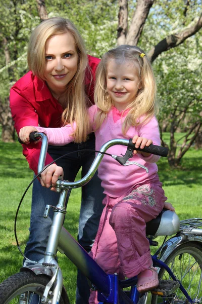 Mãe com filha na bicicleta no jardim da primavera — Fotografia de Stock
