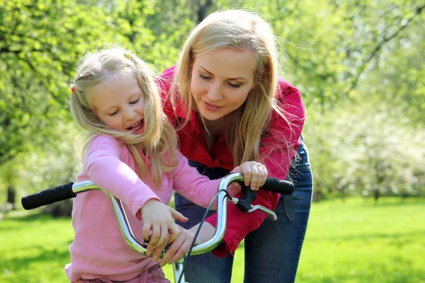 Mãe com filha na bicicleta no jardim da primavera — Fotografia de Stock
