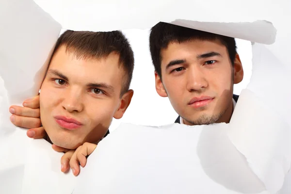 Двоє молодих чоловіків дивляться в дірку в папері — стокове фото