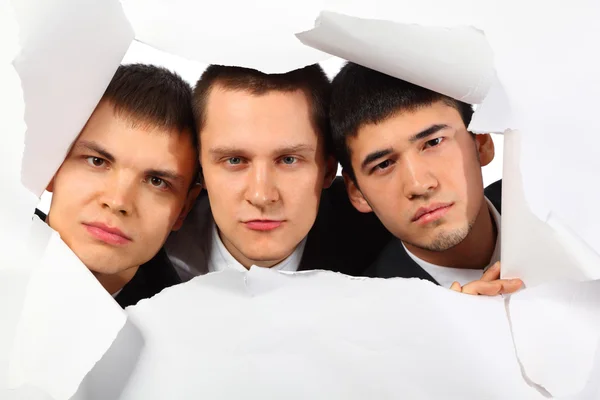 Drie jonge mannen op zoek in gat in papier — Stockfoto