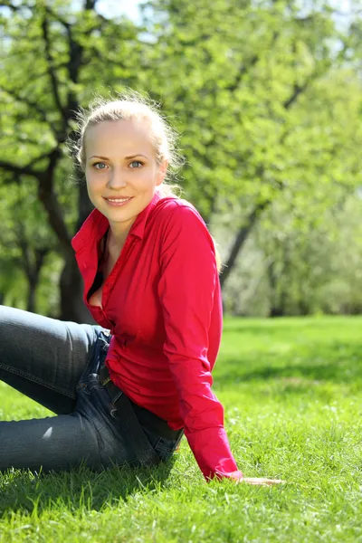 Mooie blonde zit op gras in de tuin in het voorjaar van — Stockfoto