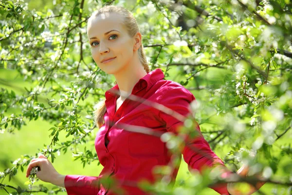 Beautiful blonde in blossoming garden in spring — Stock Photo, Image