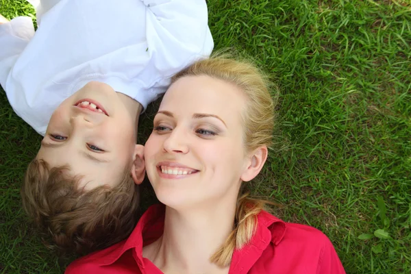Mother and son lie head to head on grass — Stock Photo, Image
