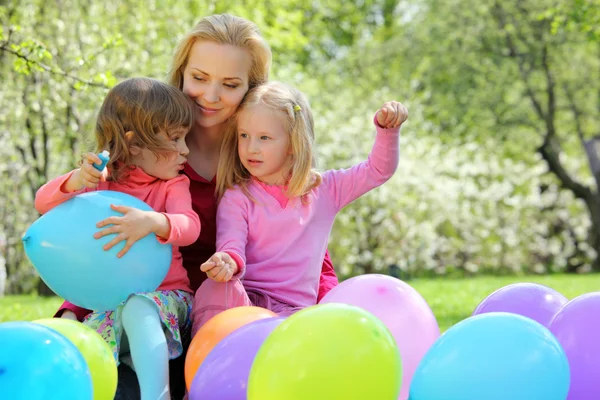 Мать, дочери и воздушные шары в саду весной — стоковое фото