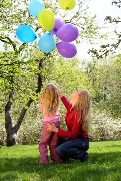 Madre con figlia con covone di palloncini in giardino in primavera — Foto Stock