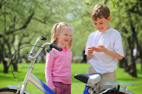 Menina, menino e bicicleta no parque na primavera — Fotografia de Stock