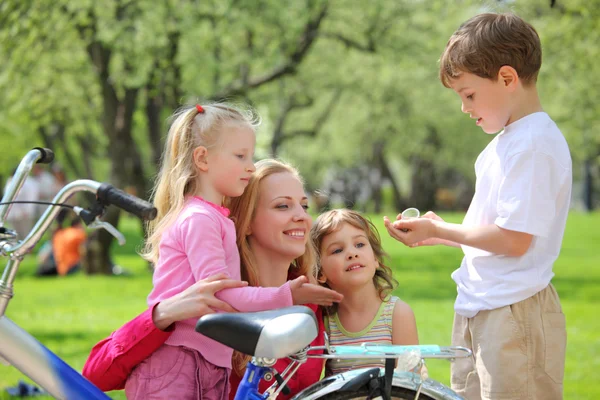 Mãe com filhos e bicicleta no parque na primavera — Fotografia de Stock