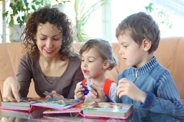 Mother and children play with jigsaw puzzle — Stock Photo, Image