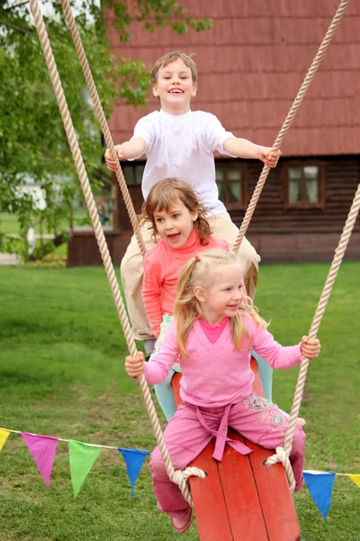 Трое детей на качелях — стоковое фото