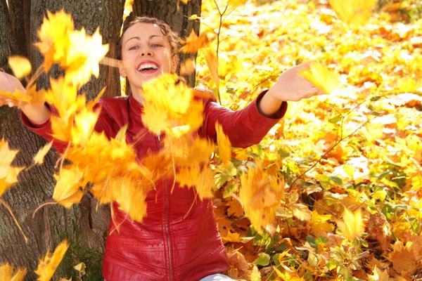 Girl throws yellow maple leaves — Stock Photo, Image