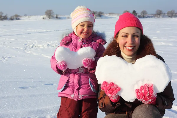 Liten flicka och mamma med snöiga hjärtan — Stockfoto