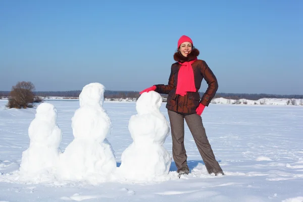 Mladá kráska žena a tři snowmans — Stock fotografie