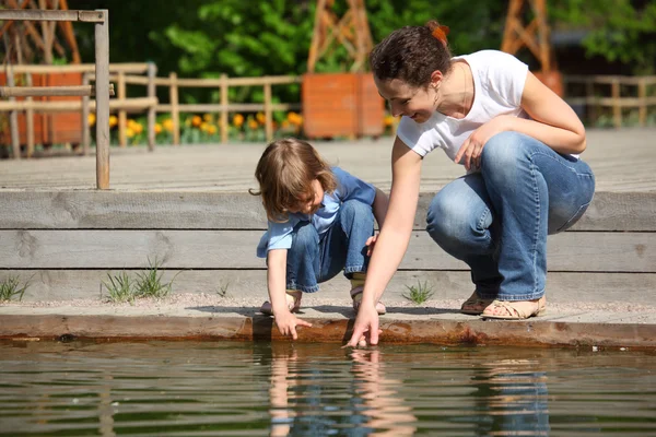 Matka z córką w parku w basenie dotknąć wody — Zdjęcie stockowe