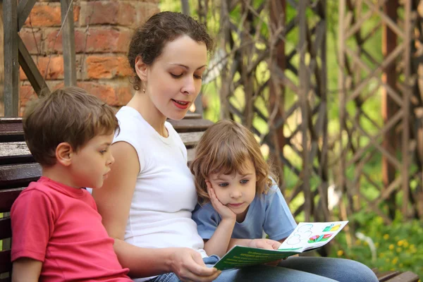 Mother reads book for children sits on bench — Stock Photo, Image