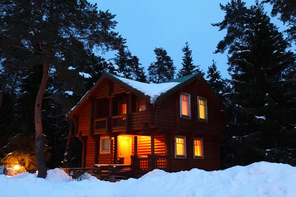 Деревянный дом в зимнем лесу в сумерках — стоковое фото