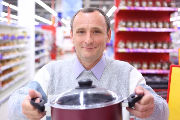Oudere man in winkel met pan in handen — Stockfoto