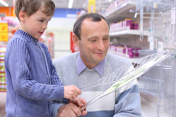 Elderly man with boy in store with grill for roasting in hands