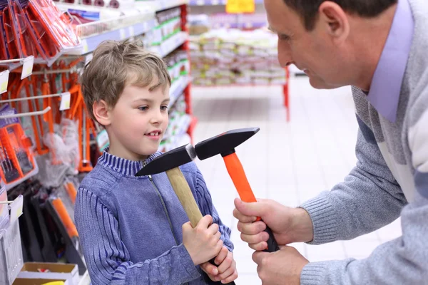 Uomo anziano con ragazzo in negozio con martelli in mano — Foto Stock