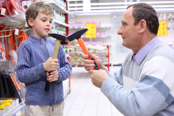 Літній чоловік з хлопчиком в магазині з молотками в руках — стокове фото