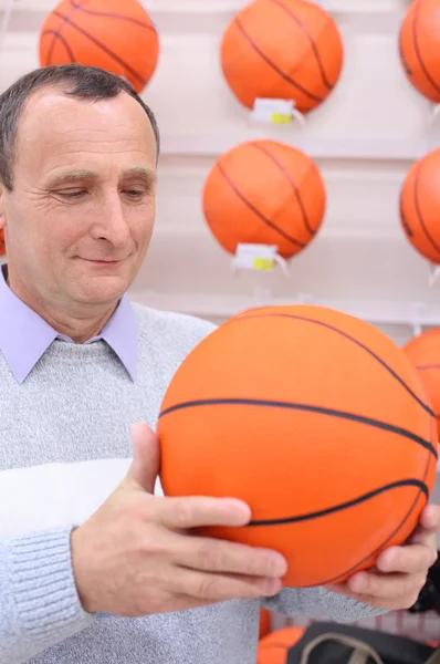 Oudere man in winkel met basketbal bal in handen — Stockfoto