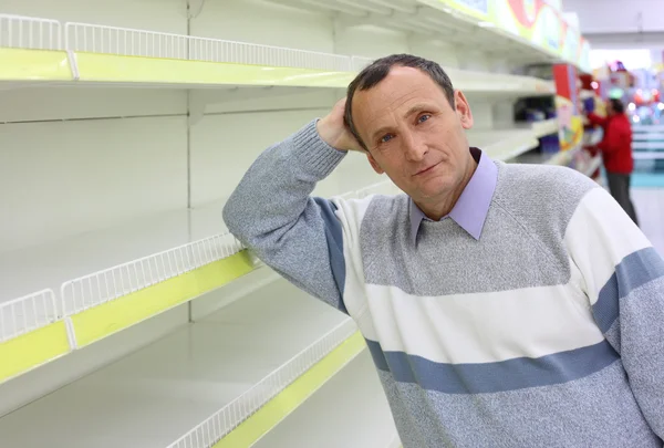 Vieil homme se penche contre les étagères vides dans le magasin — Photo