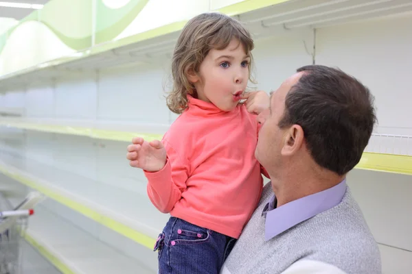 Elderly man at empty shelves in shop with child on hands — Stock Photo, Image
