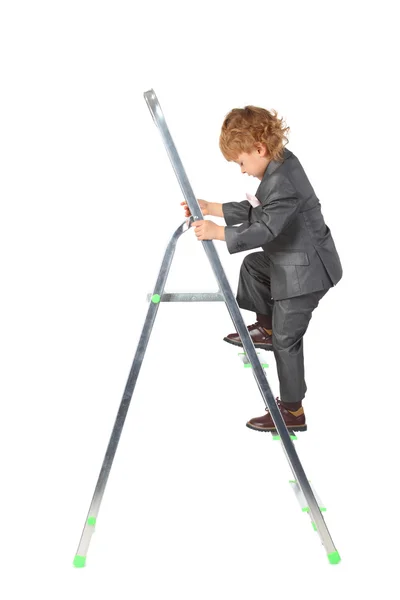 Jongen in pak stijgt op stap-ladder — Stockfoto